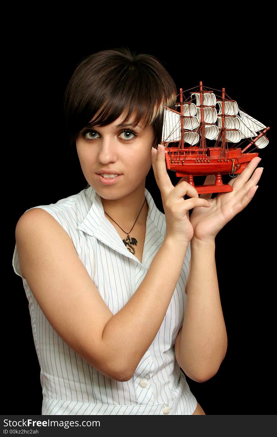 The nice girl with the toy ship in a hand, isolated on black background