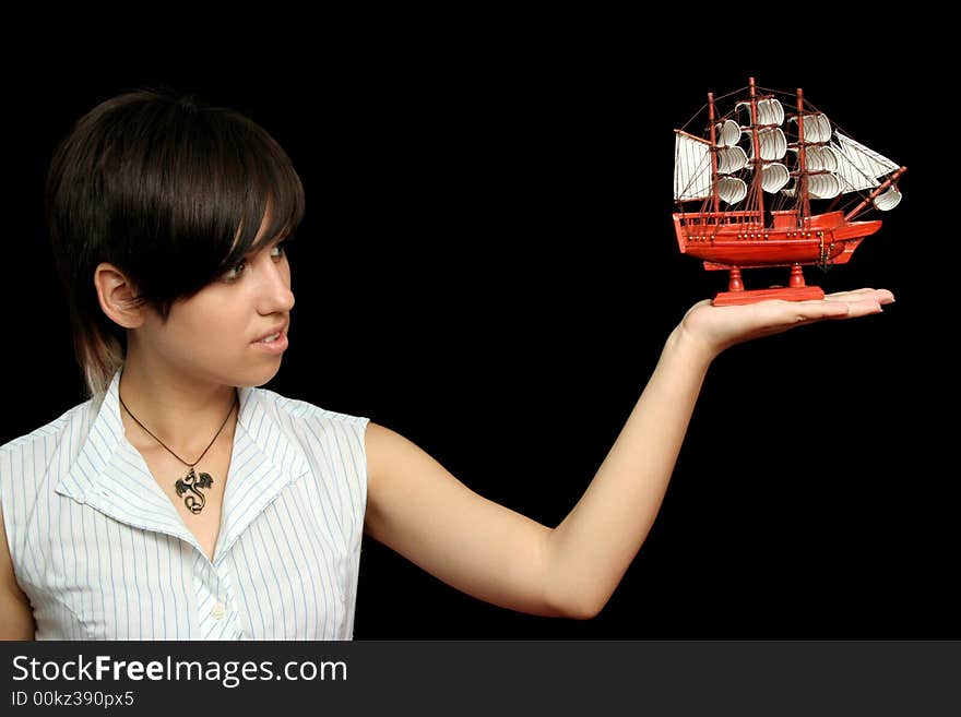 The nice girl with the toy ship in a hand, isolated on black background. The nice girl with the toy ship in a hand, isolated on black background