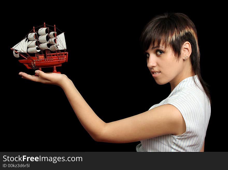 The nice girl with the toy ship in a hand, isolated on black background