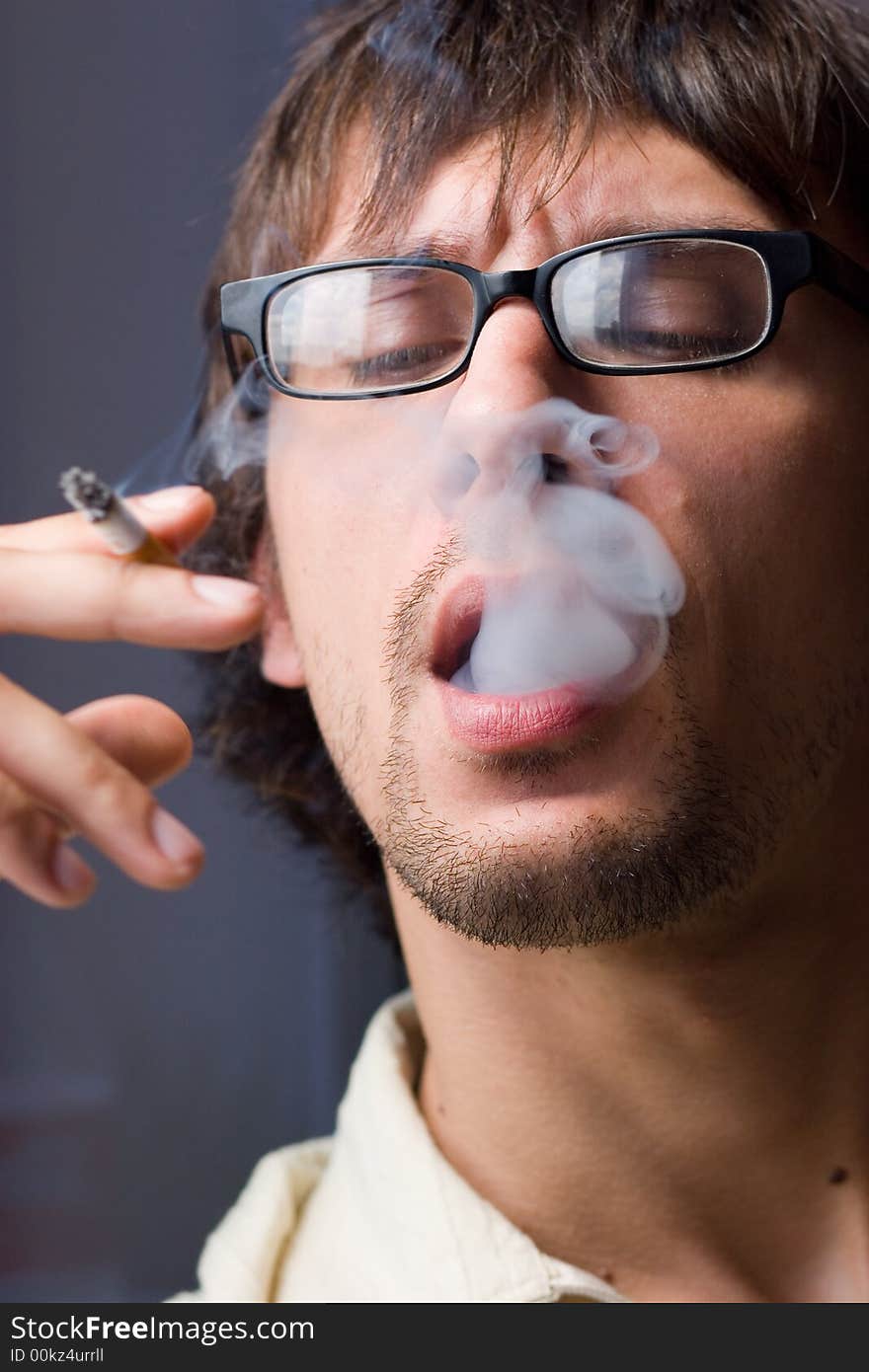 Young man with glasses a-smoke. Young man with glasses a-smoke