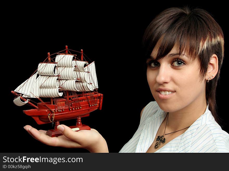 The nice smiling girl with the toy ship in a hand, isolated on black background