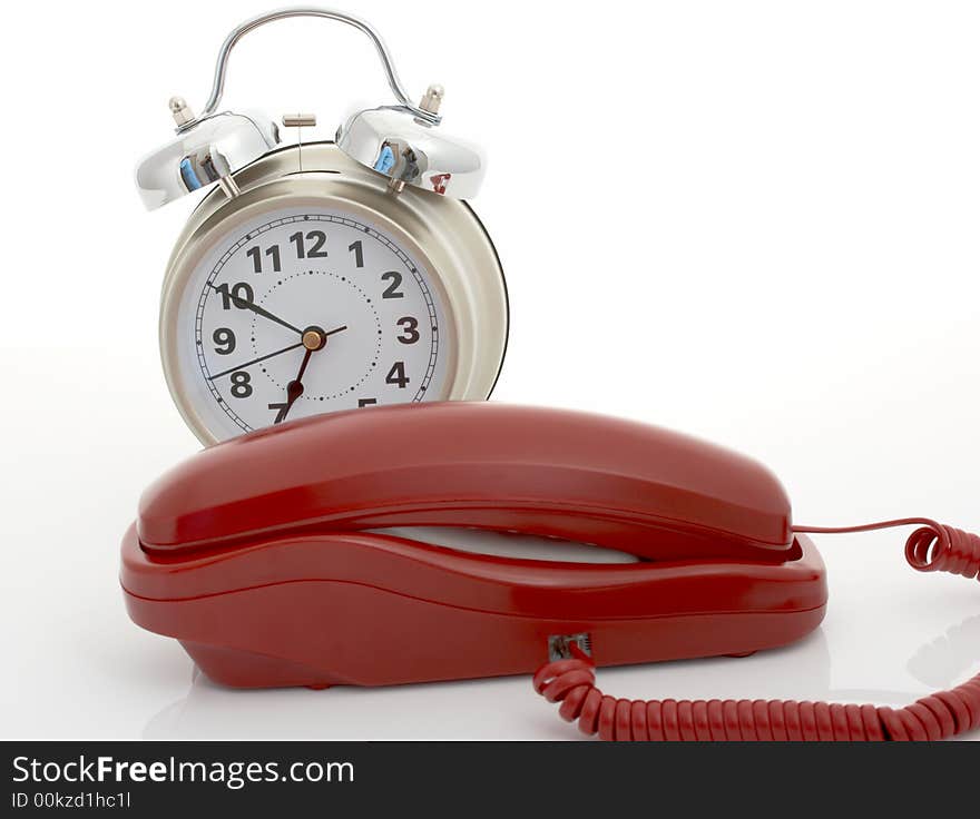 Photo of a telephone and an alarm clock over a white background. Photo of a telephone and an alarm clock over a white background