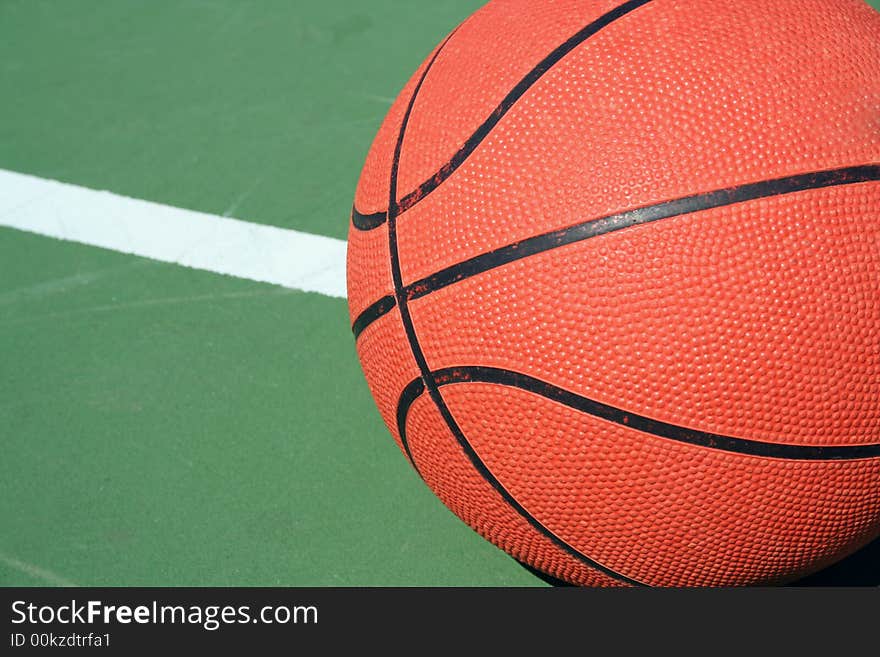 A Basketball on green court with white line. A Basketball on green court with white line