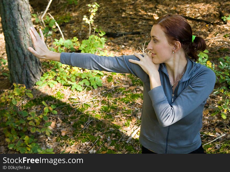 A woman practices stretching in autumn forest