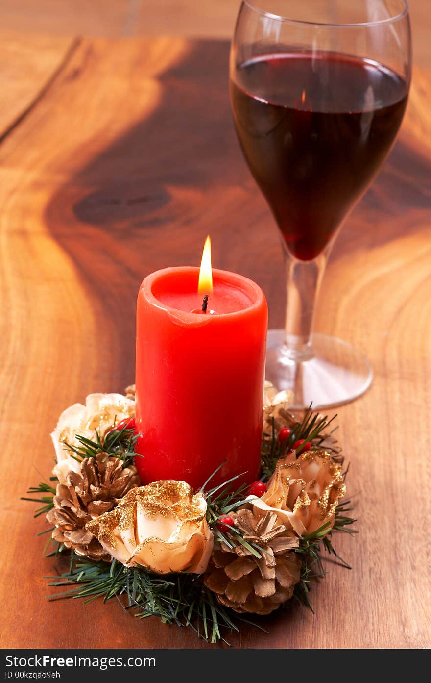 Christmas candle and a glass of wine on a wooden table. Christmas candle and a glass of wine on a wooden table