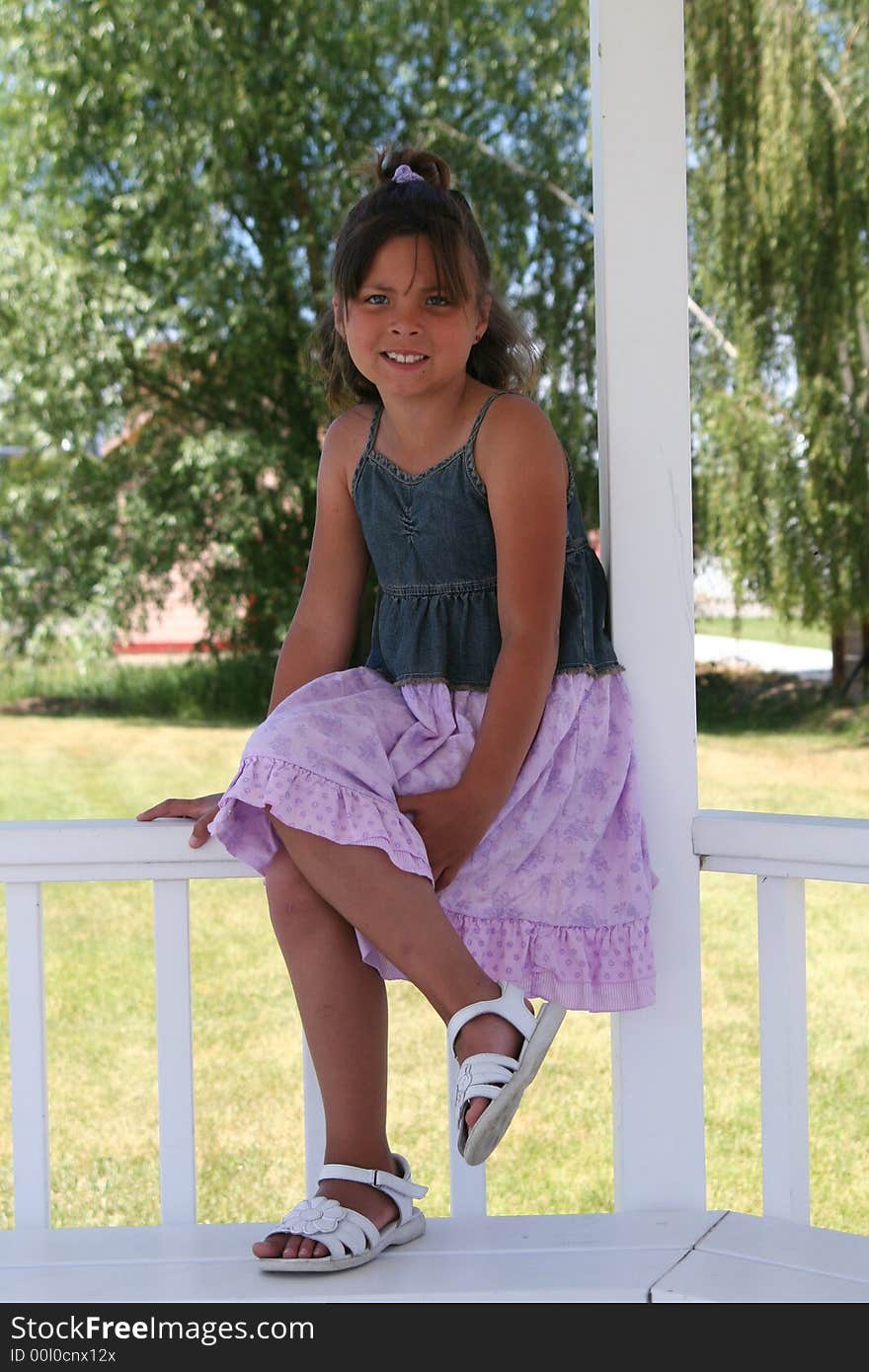 Girl sitting on a fence in the sun. Girl sitting on a fence in the sun