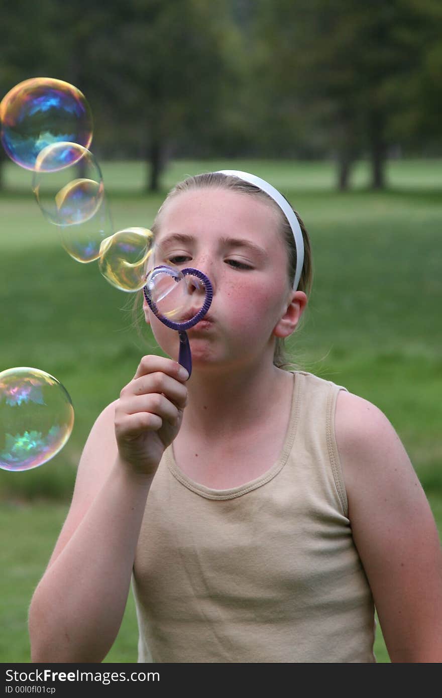 Little teen girl blowing bubbles.