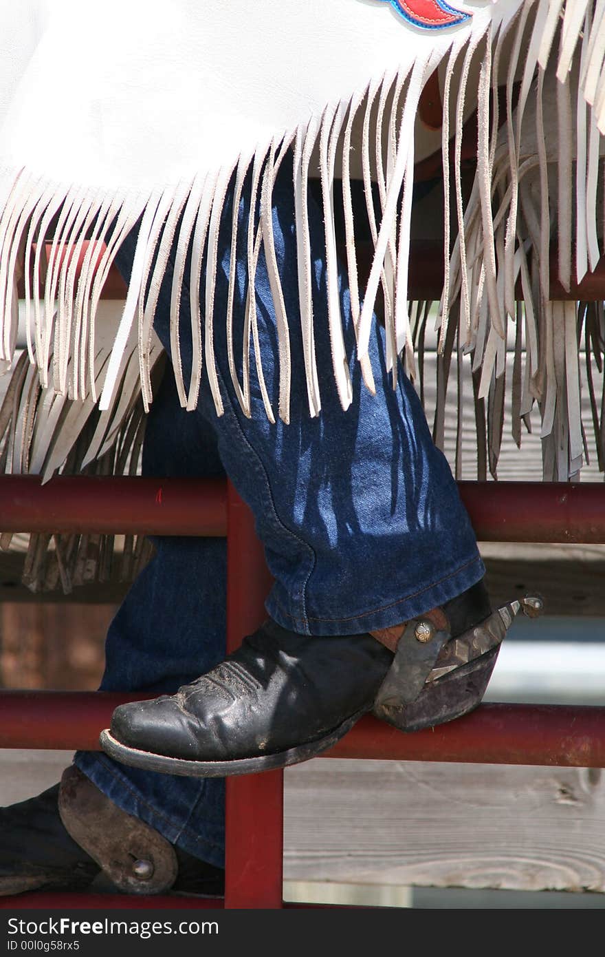 Cowboy boot with a spur and shaps on the gate. Cowboy boot with a spur and shaps on the gate