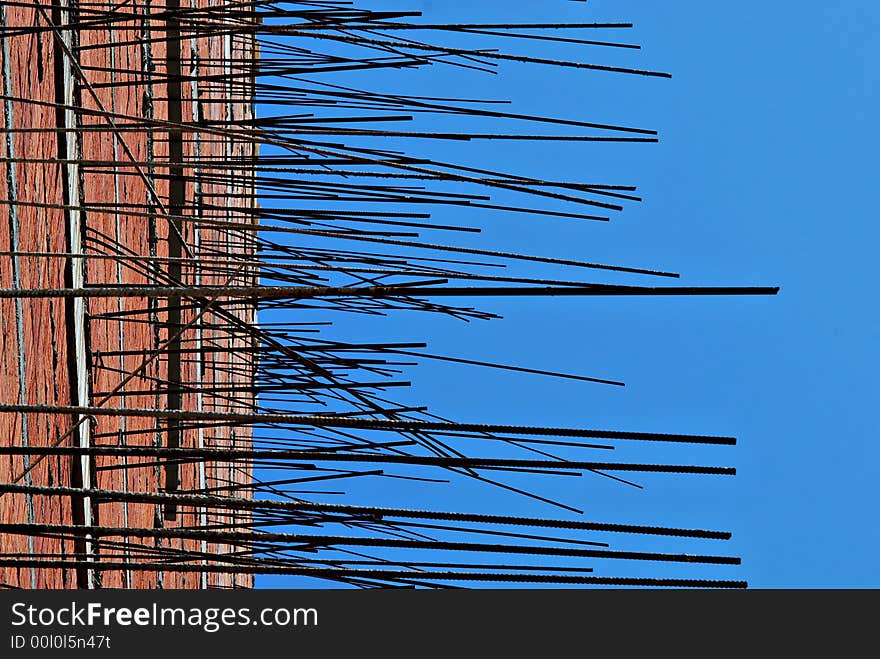 Unfinished side of building with protruding steel elements itno the blue sky. Unfinished side of building with protruding steel elements itno the blue sky