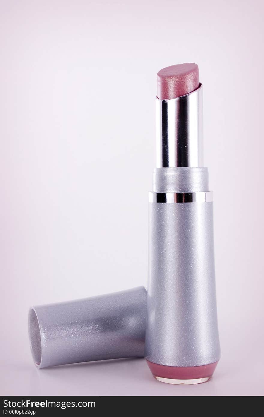 An opened tube of pinklipstick on a slightly pink vignetted background.