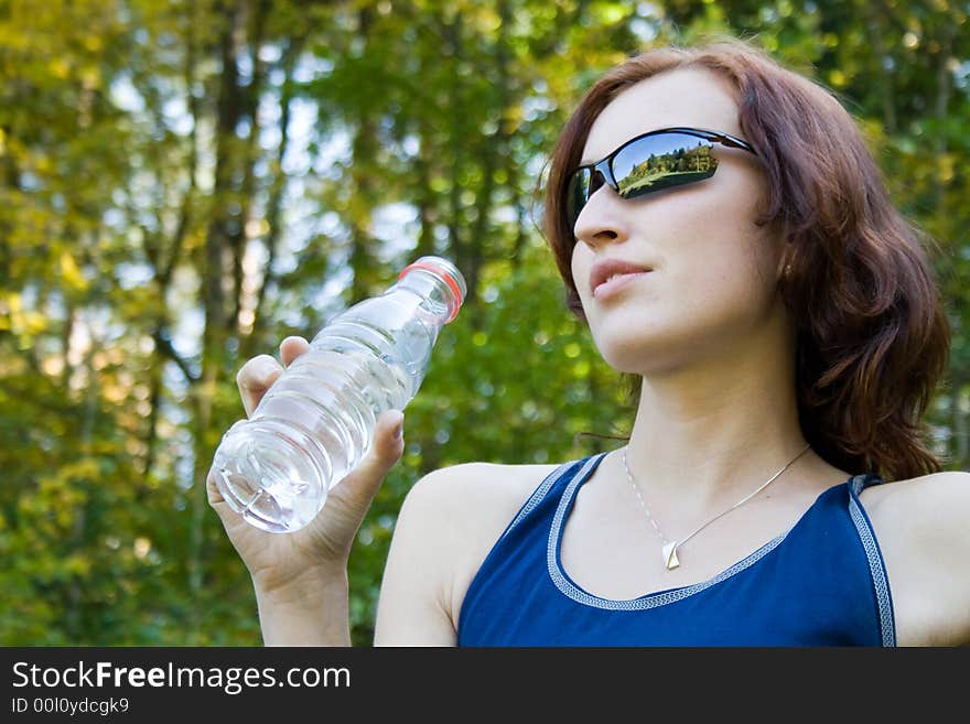 A young woman is drinking from bottle. A young woman is drinking from bottle