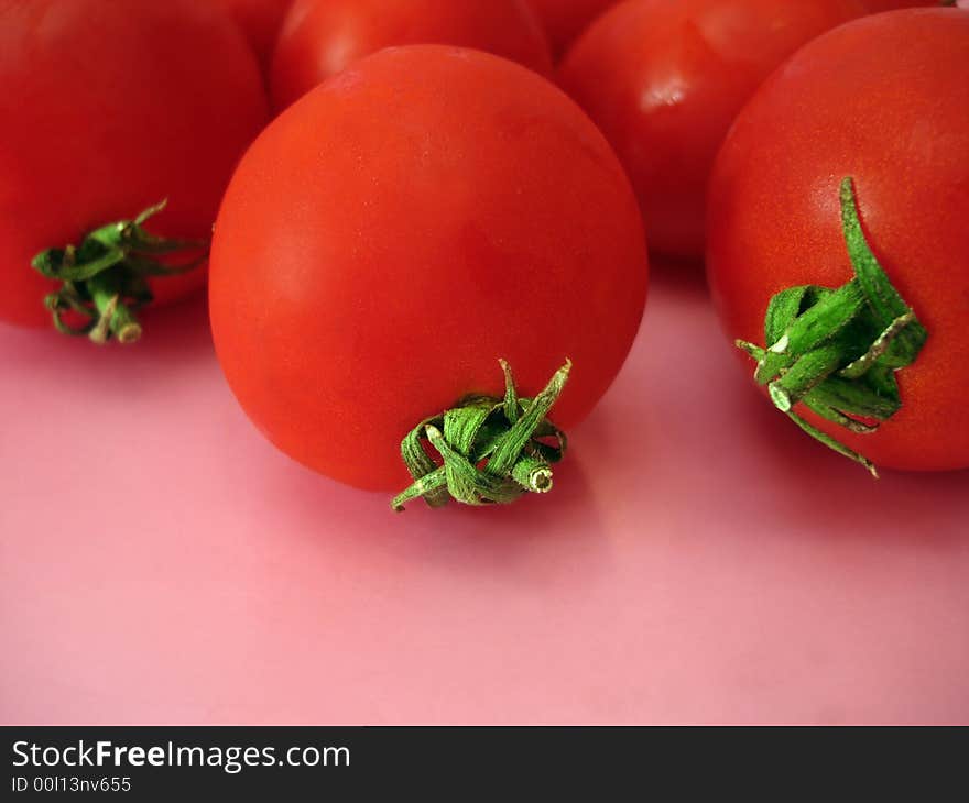 Many tomatoes over pink background