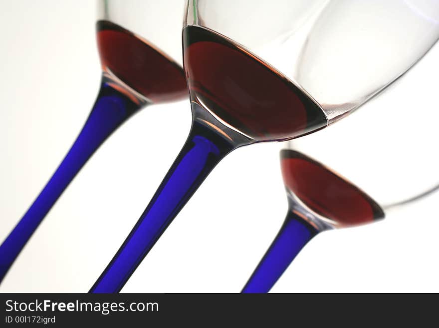 Three glasses of red wine with blue stems on an angle. Three glasses of red wine with blue stems on an angle.