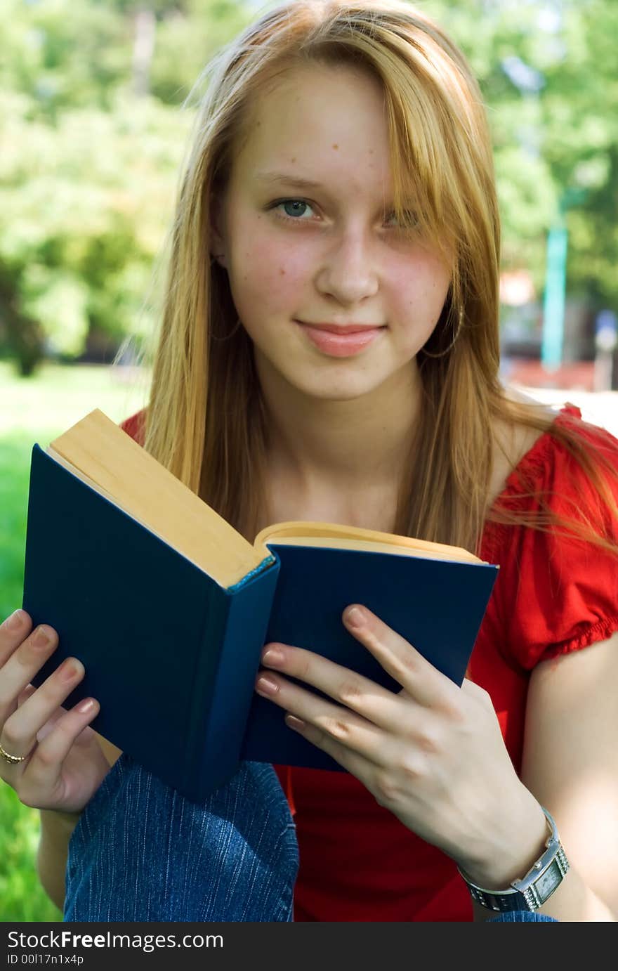 School girl readin the book and looking at camera.