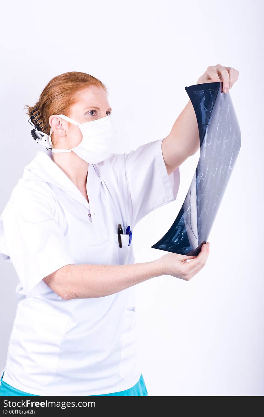 Redhaired woman doctor (or nurse) examines X-ray. White background. Redhaired woman doctor (or nurse) examines X-ray. White background.