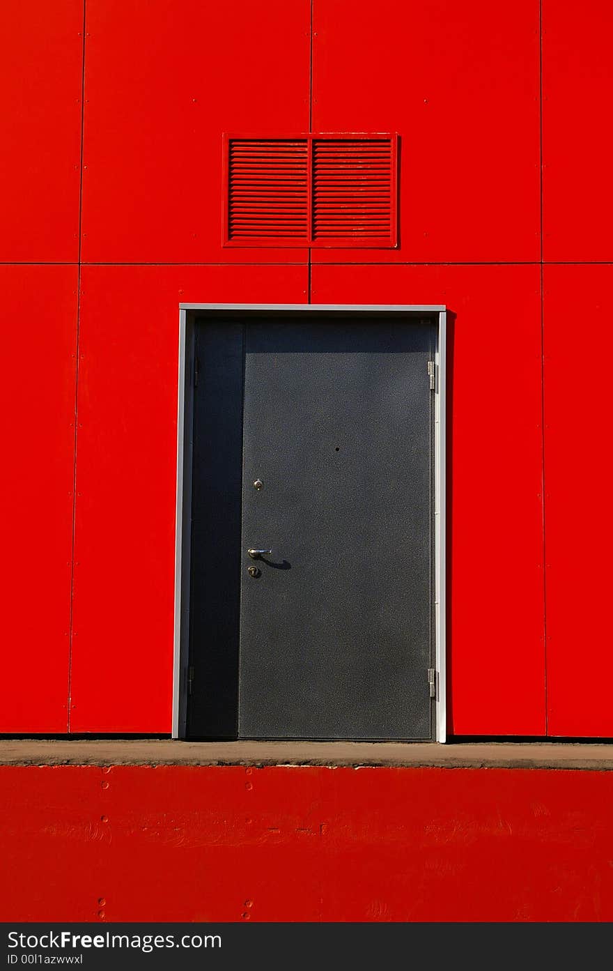 Grey door in a red wall, a part of a building