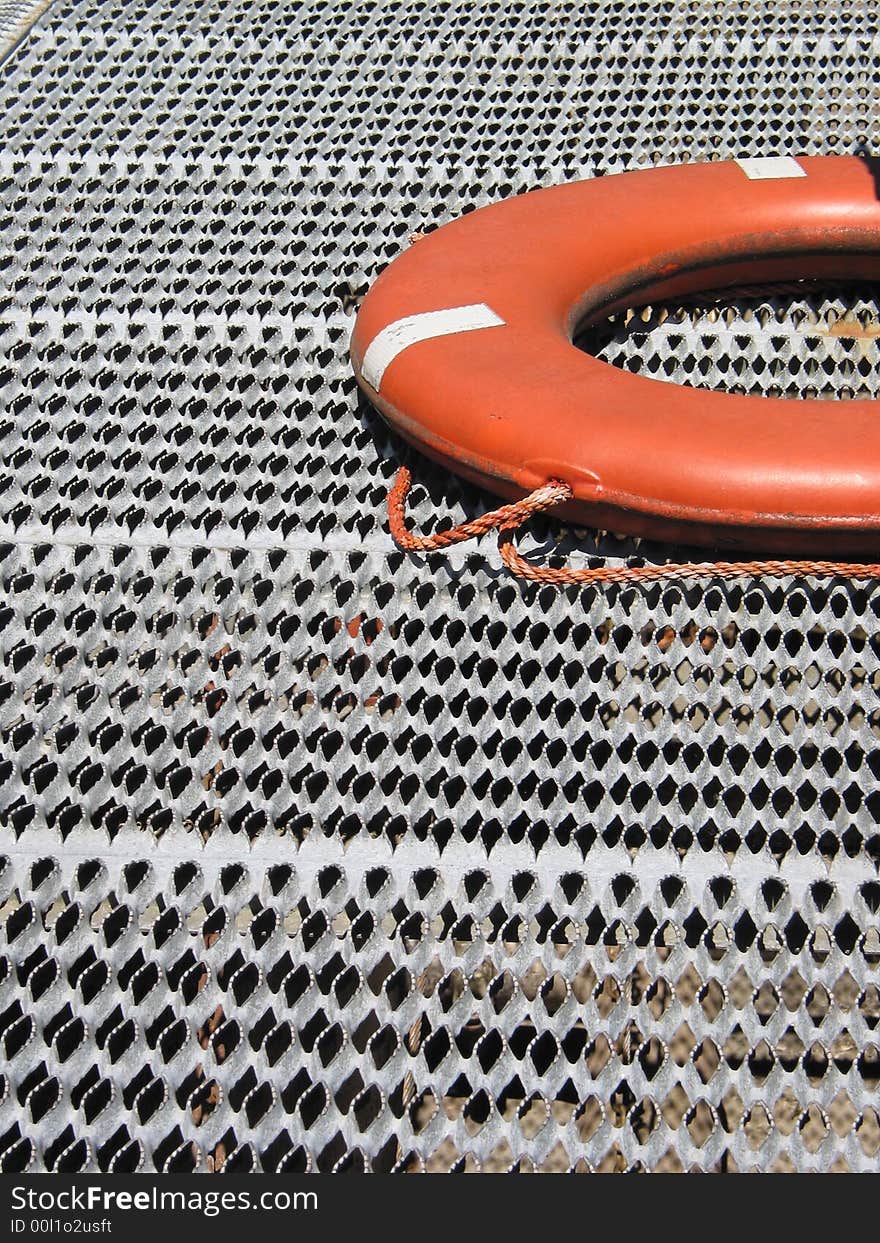 An orange life ring rests on metal grating. An orange life ring rests on metal grating.