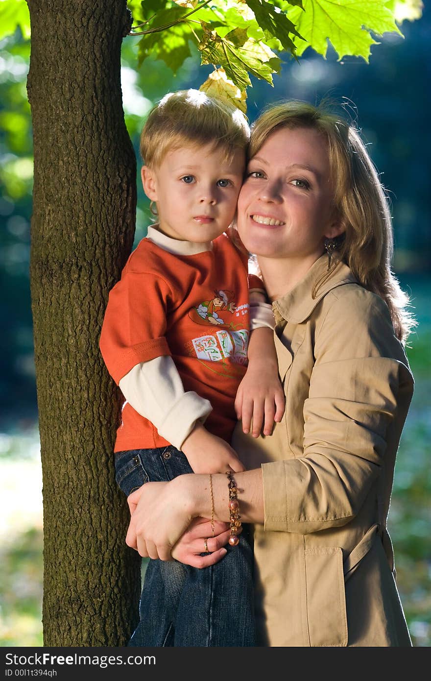 Laughing mother holds son in autumn park