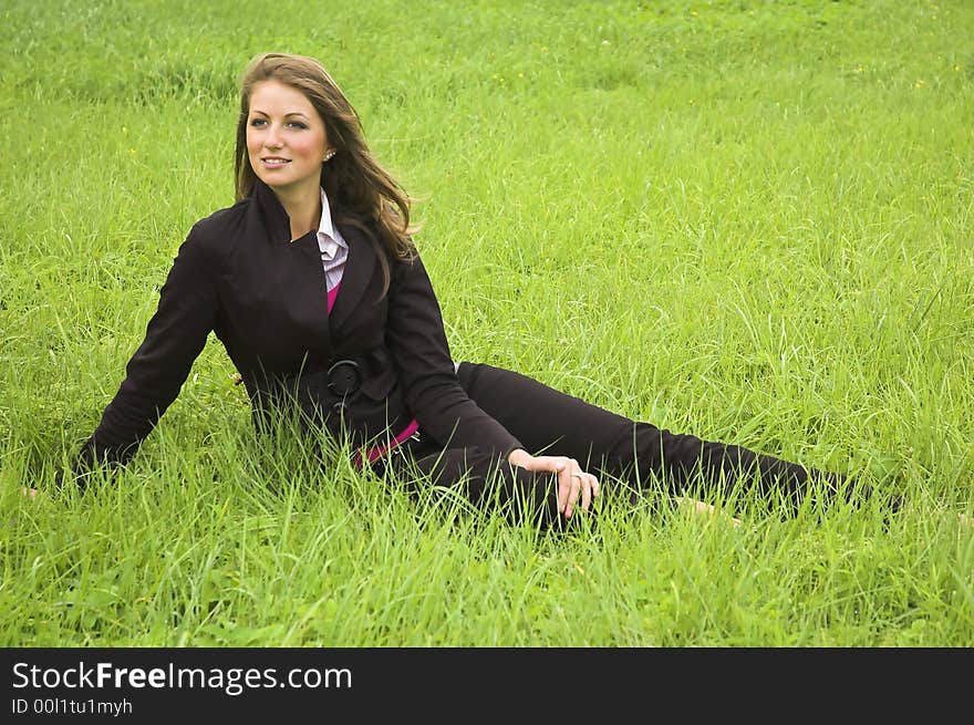 The beautiful girl sits on a green grass. The beautiful girl sits on a green grass