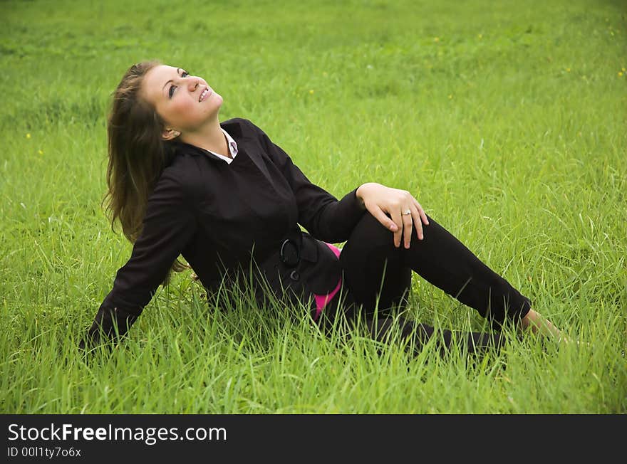 The beautiful girl sits on a green grass. The beautiful girl sits on a green grass