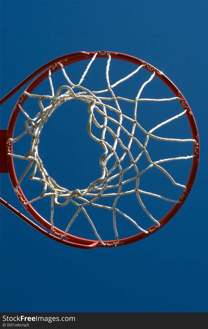 Full basketball hoop as viewed from below against a bright blue sky.