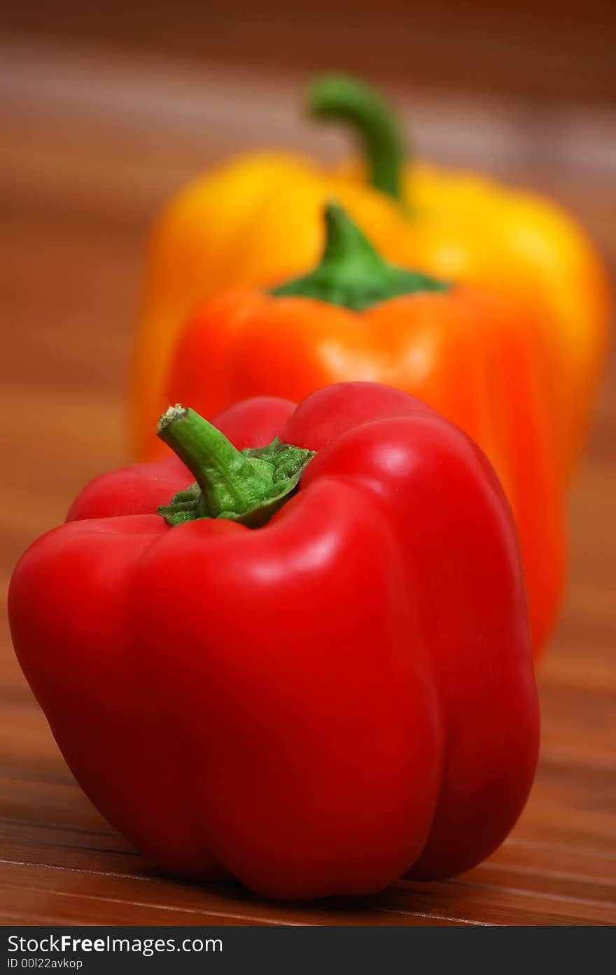 Three colorful peppers on wooden table