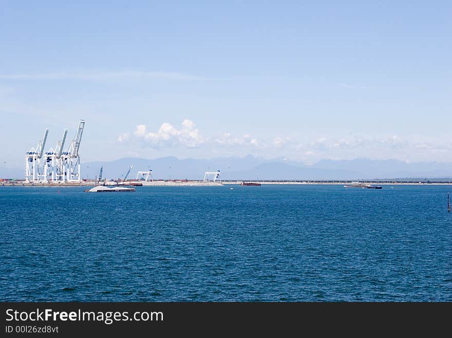 Loading cranes in Vancouver harbor with the mountains and blue sky on the background