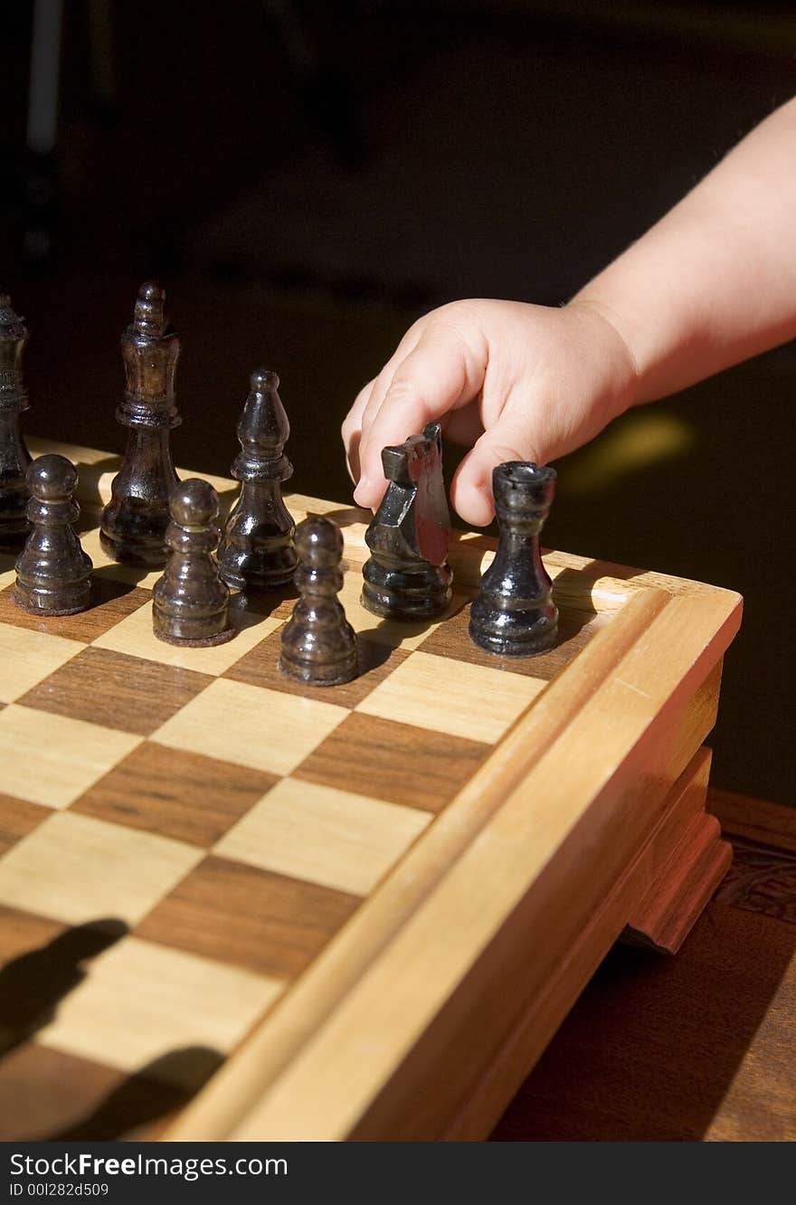 Young child playing chess on traditional wood chess set