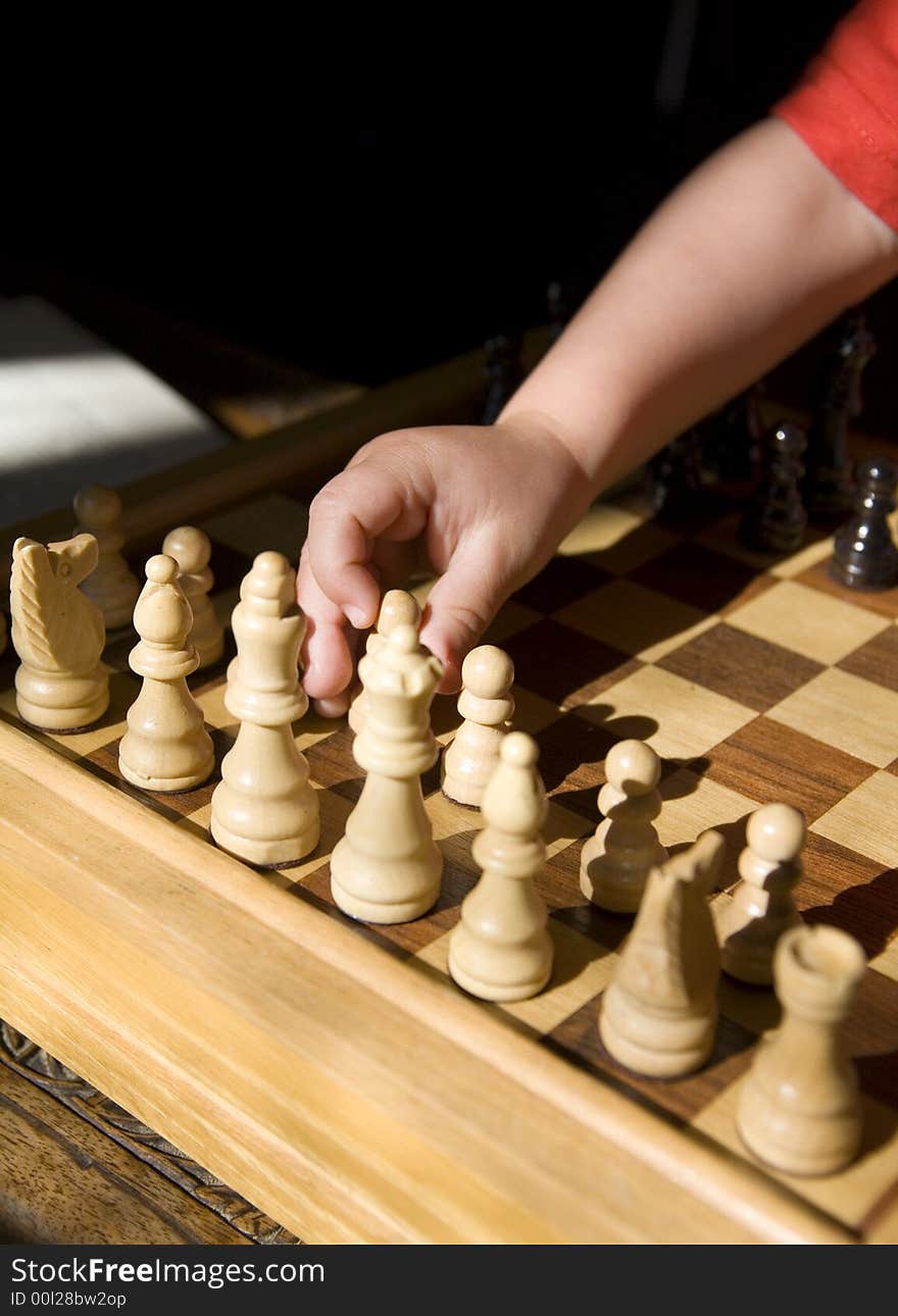 Young child playing chess on traditional wood chess set