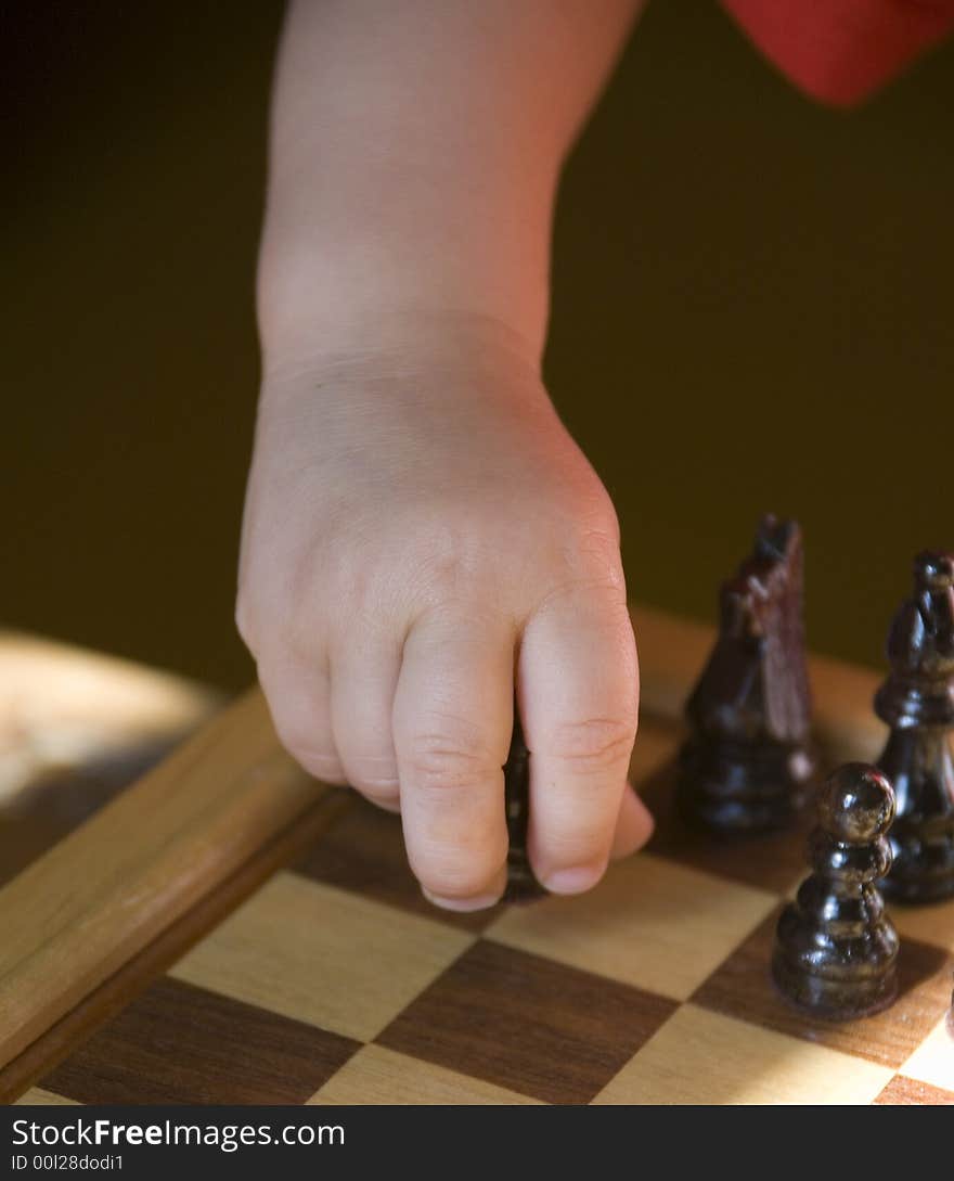 Young child playing chess on traditional wood chess set