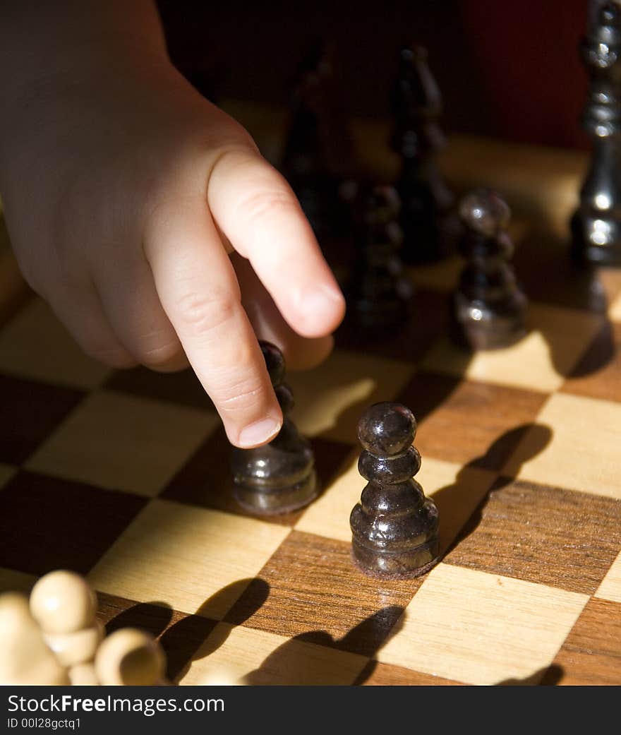 Young child playing chess on traditional wood chess set