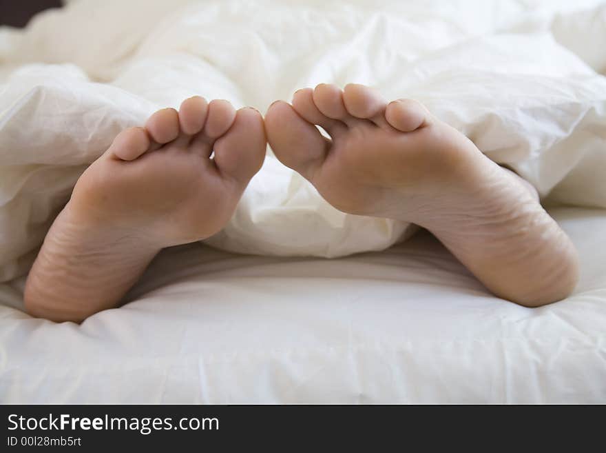 Sleeping woman's feet poking outside the duvet