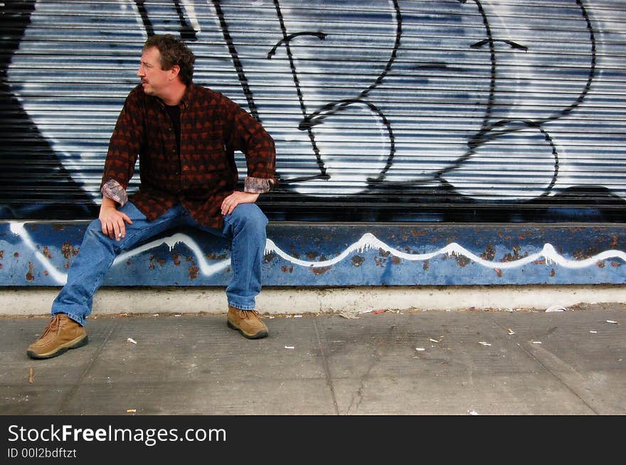 Middle-aged man smoking outside near graffiti. Middle-aged man smoking outside near graffiti