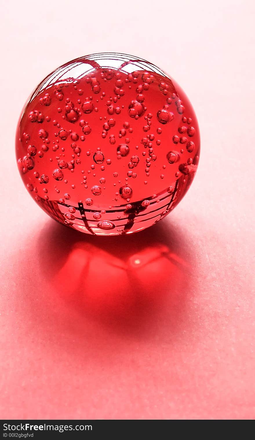 Red glass ornamental ball back lighted by open window on a red textured surface. Red glass ornamental ball back lighted by open window on a red textured surface.