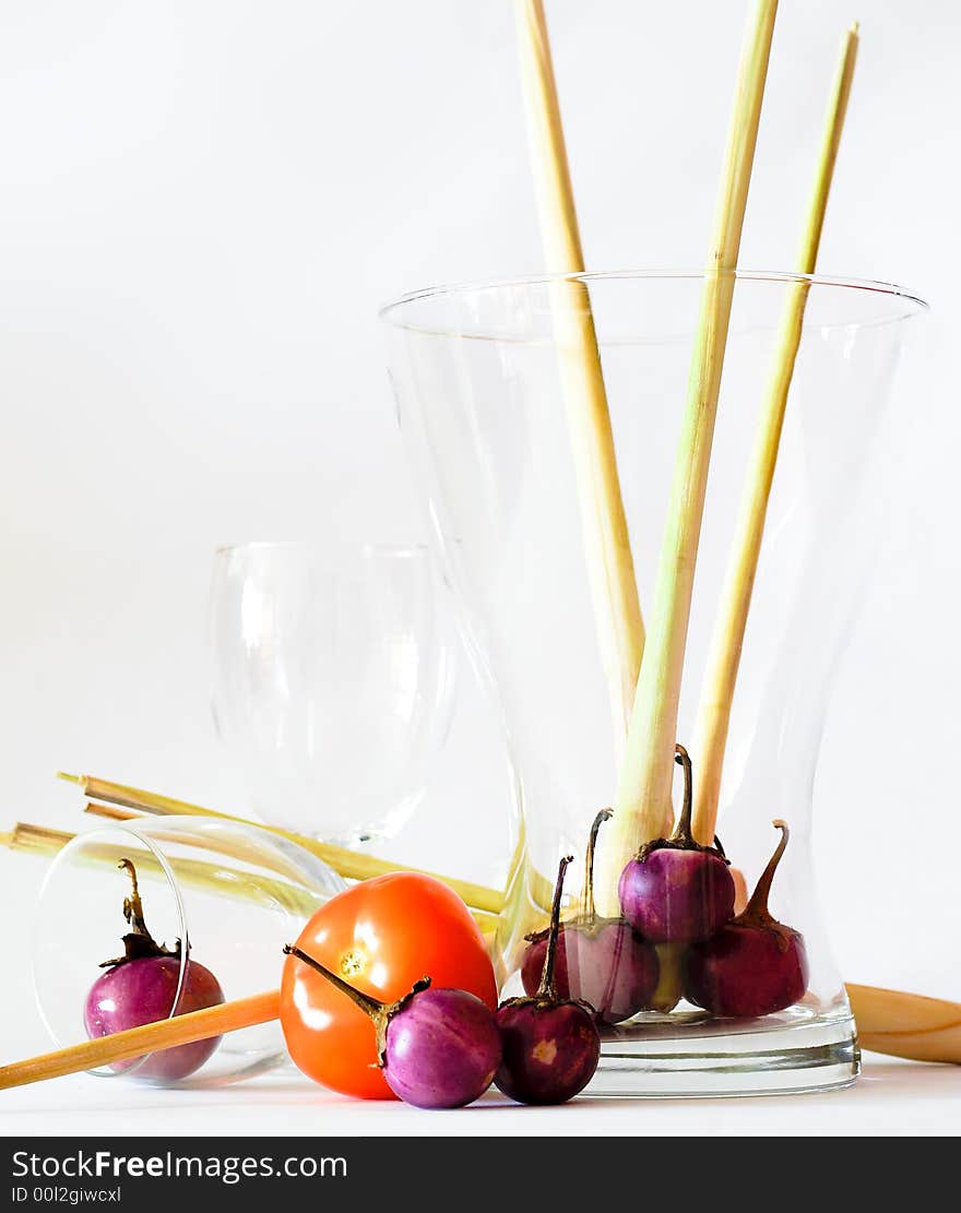 Still life of the ingredients of green curry, namely lemon grass, mini brinjals, or eggplant, and a single tomato, in various glassware including wine glasses. Still life of the ingredients of green curry, namely lemon grass, mini brinjals, or eggplant, and a single tomato, in various glassware including wine glasses.