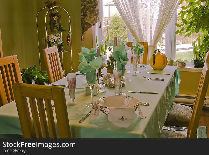 Table setting for a family dinner with green tablecloth and napkins. Table setting for a family dinner with green tablecloth and napkins