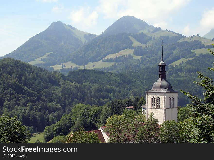 Belltower of a church with the Swiss Alps in the background. Belltower of a church with the Swiss Alps in the background.