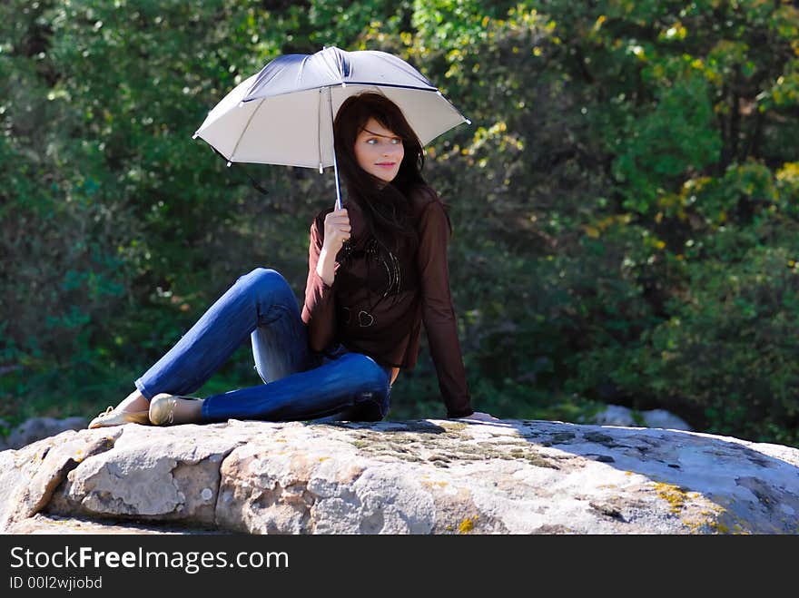 Smilling girl with umbrella on the stone