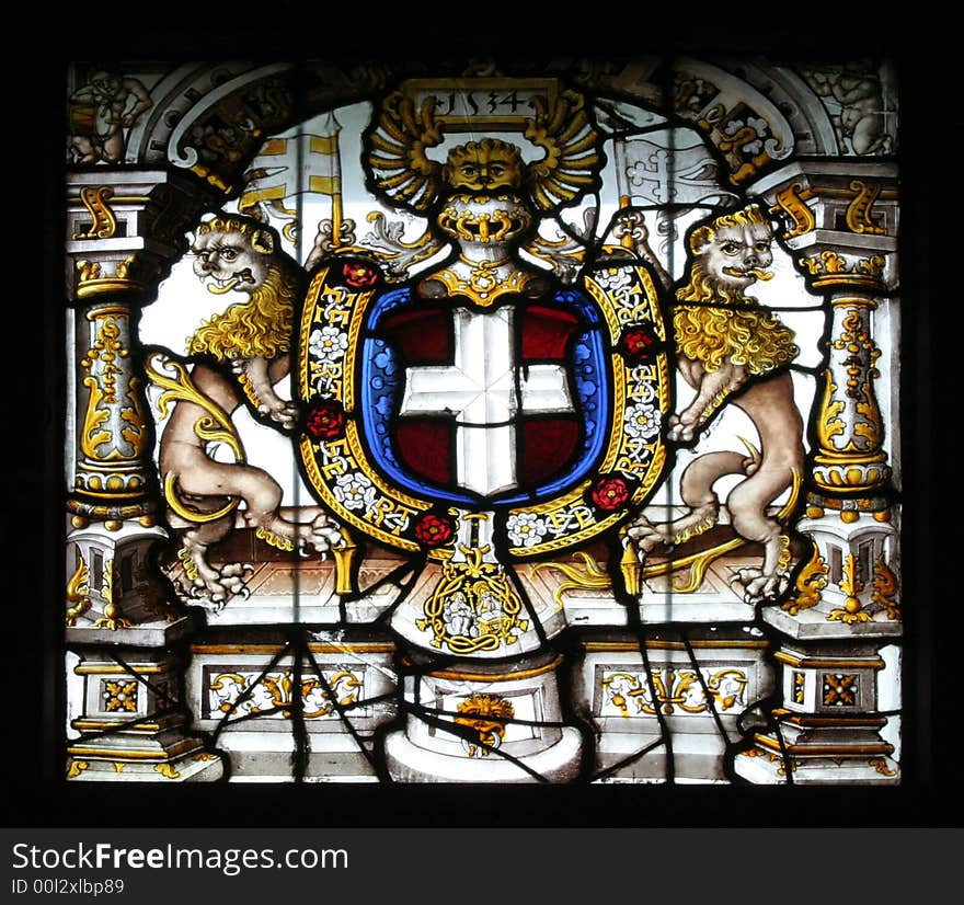 Stained glass found in the castle of Gruyeres. It represents an emblem with a cross in the middle and two stylized lions on the sides.