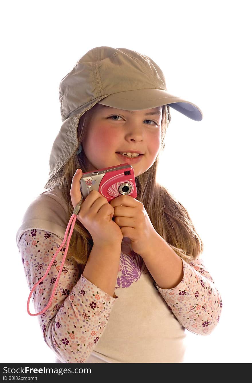 A cute young girl smiles while wearing a cap and holding a camera. Isolated against a white background. A cute young girl smiles while wearing a cap and holding a camera. Isolated against a white background.