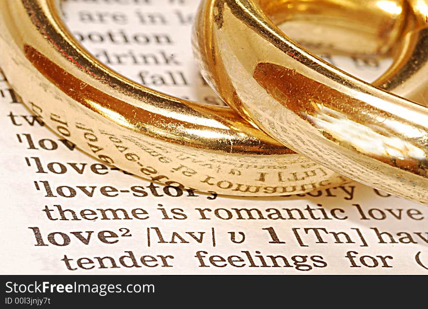 The word wedding out of a dictionary with gold rings next to it. The word wedding out of a dictionary with gold rings next to it