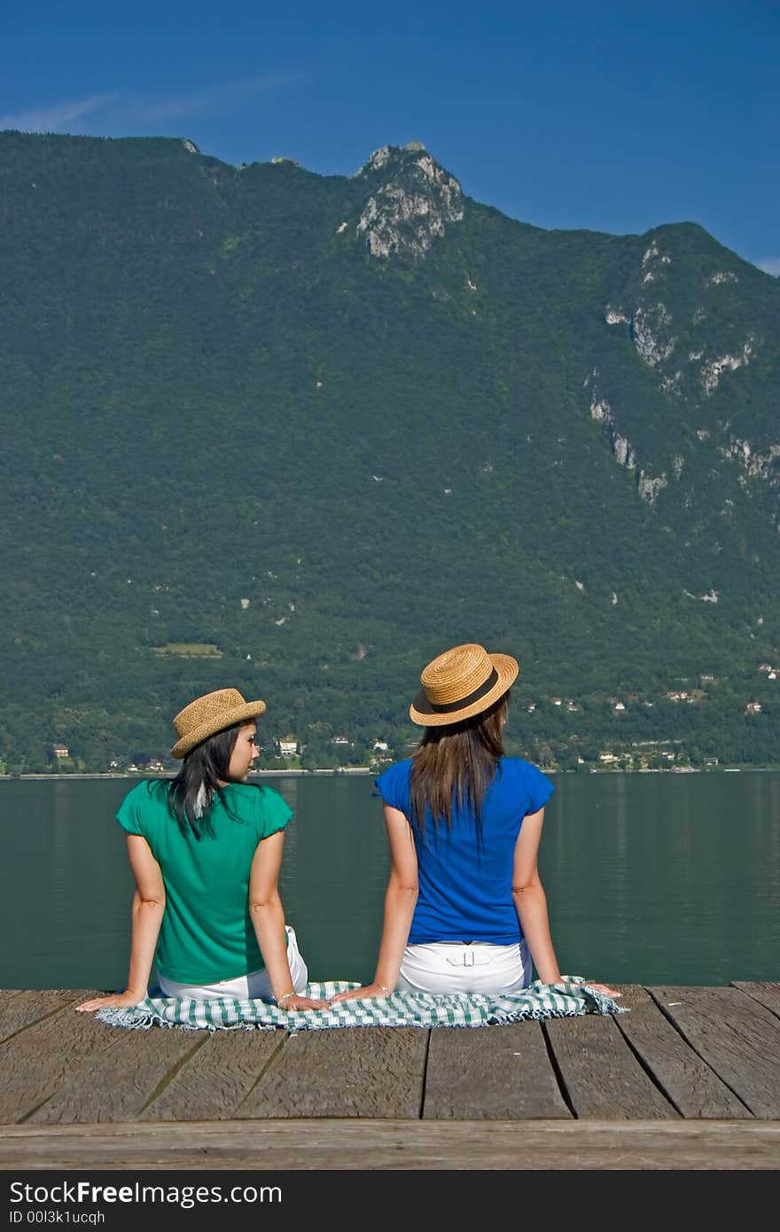 Young woman sitting on a pontoon at the edge of a lake. Young woman sitting on a pontoon at the edge of a lake