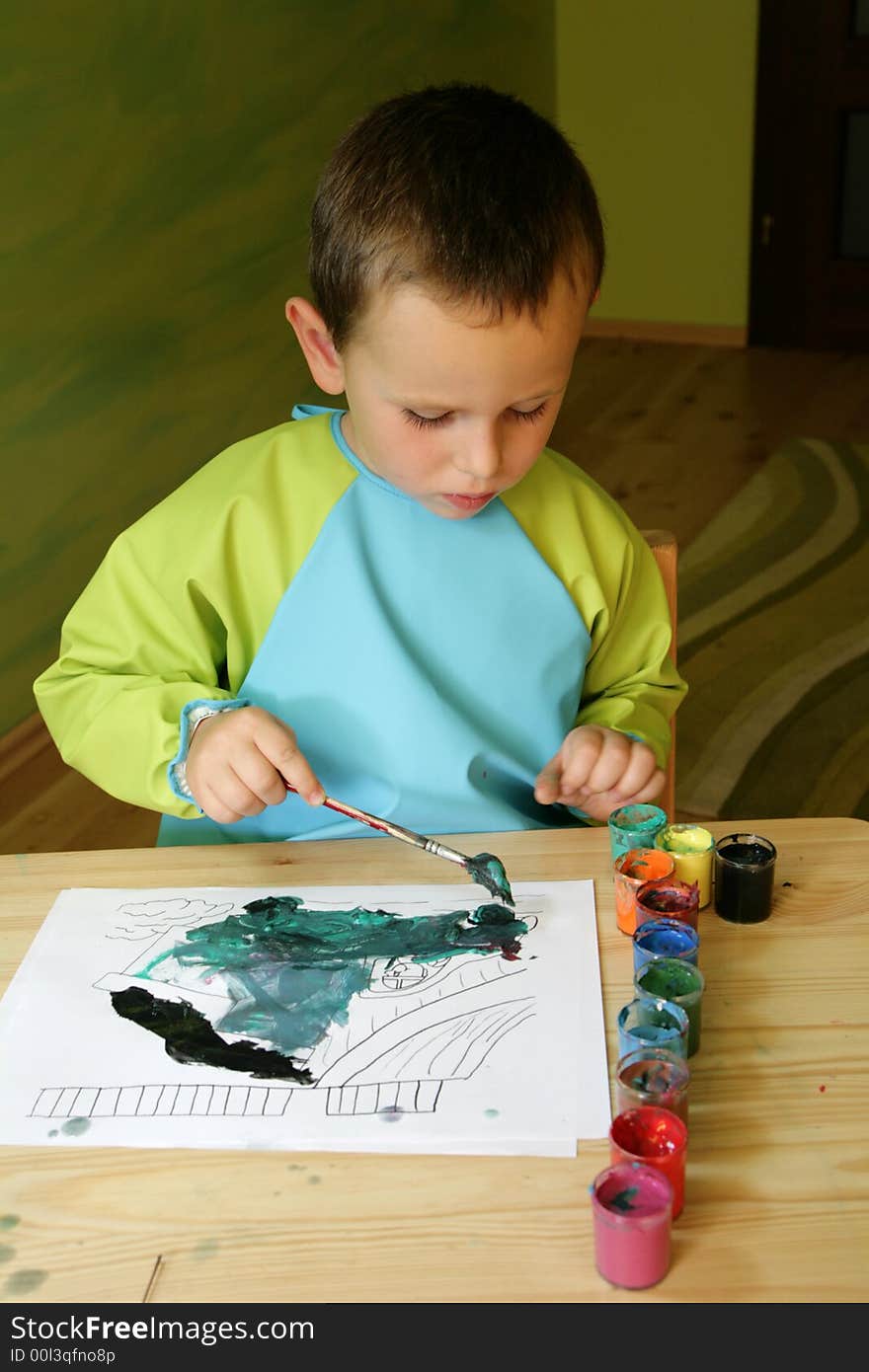 3 years old boy painting a picture with a paintbrush and water colors at a table. 3 years old boy painting a picture with a paintbrush and water colors at a table.