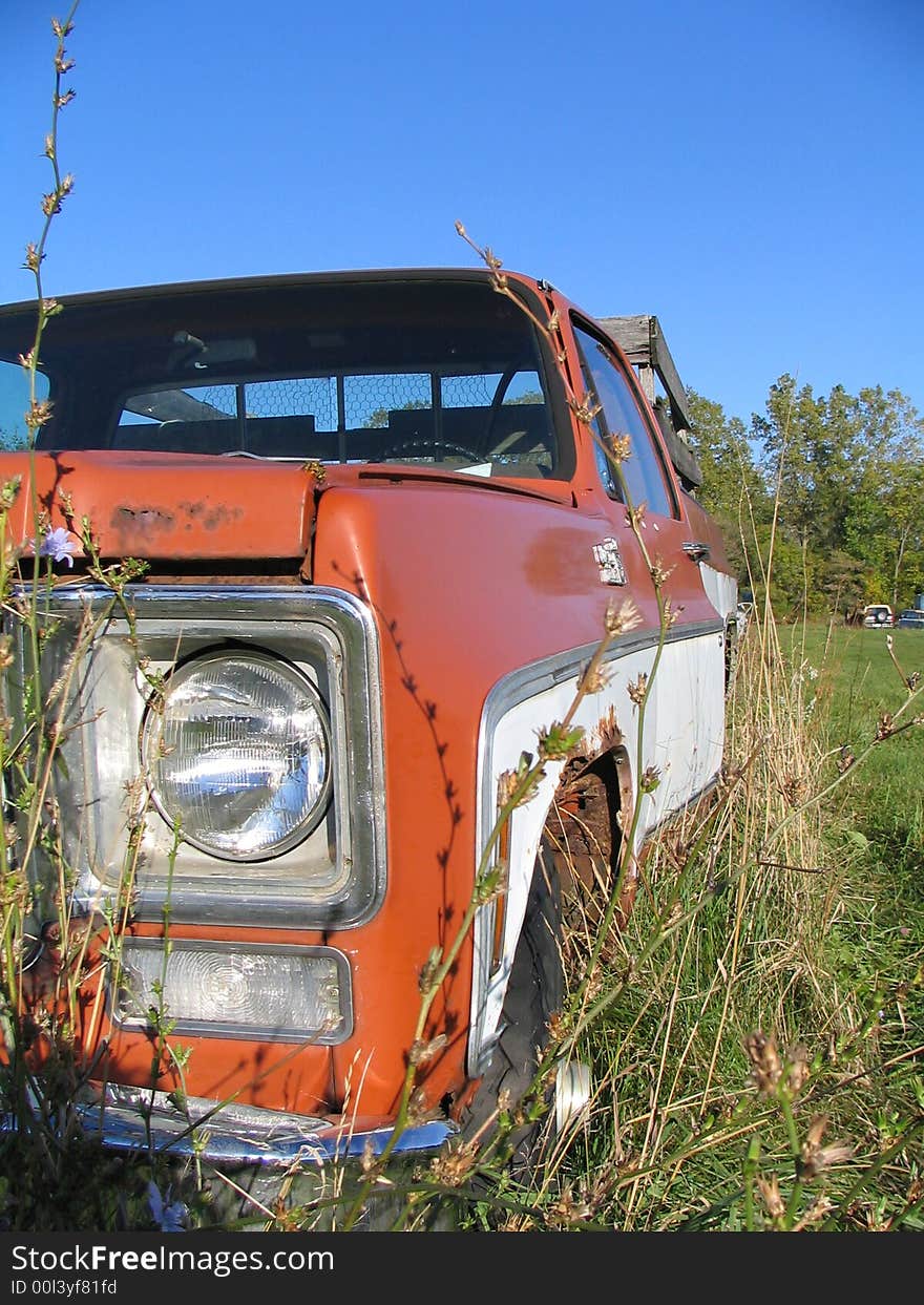 An old rusty truck sitting in the weeds. An old rusty truck sitting in the weeds.