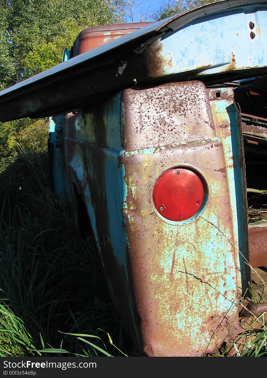 The taillight of a truck sitting in the weeds in a junk yard. The taillight of a truck sitting in the weeds in a junk yard.