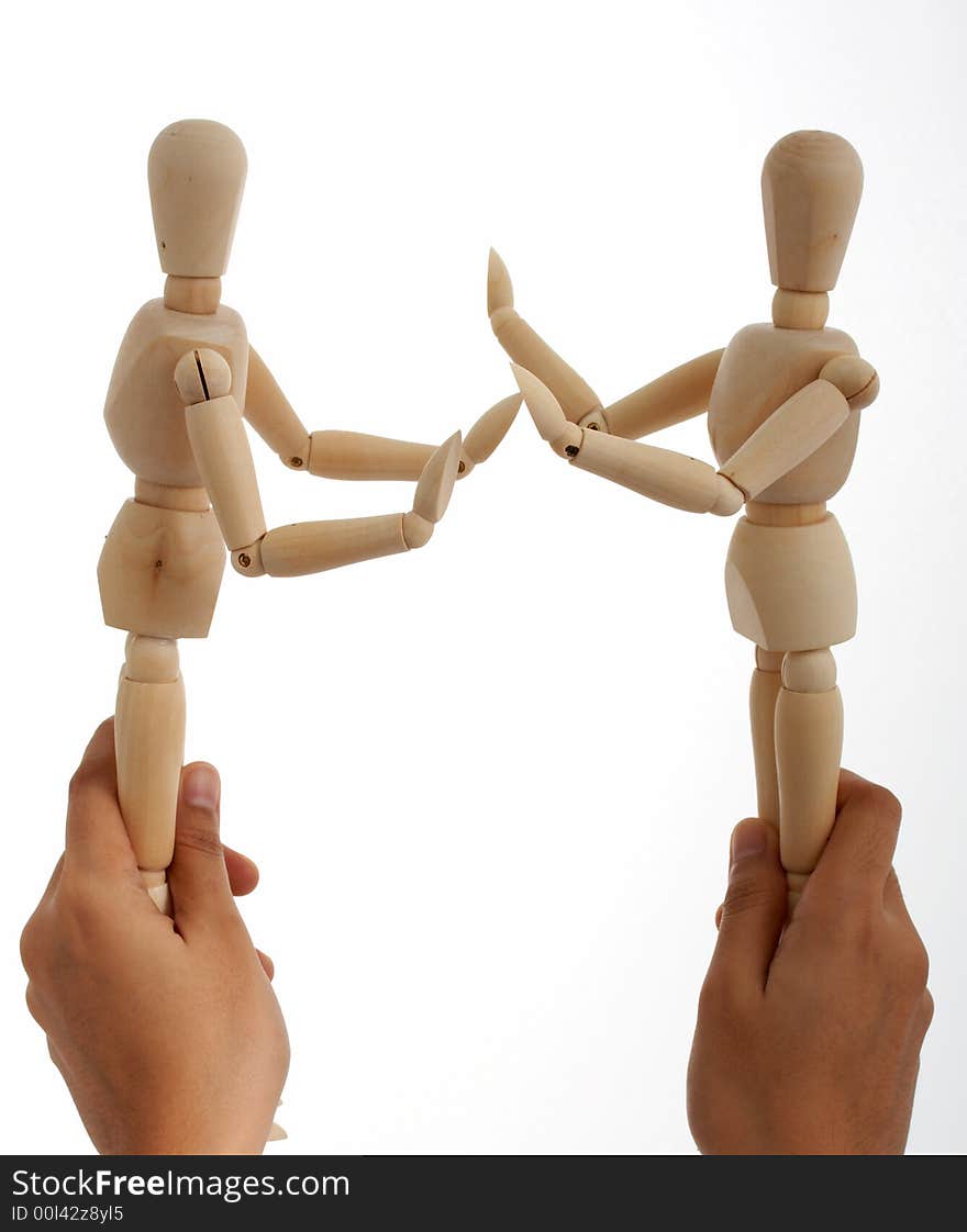 Holding two wooden figure over a white background