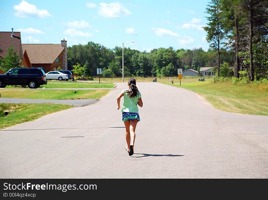 Young athletic girl running along a road. Young athletic girl running along a road