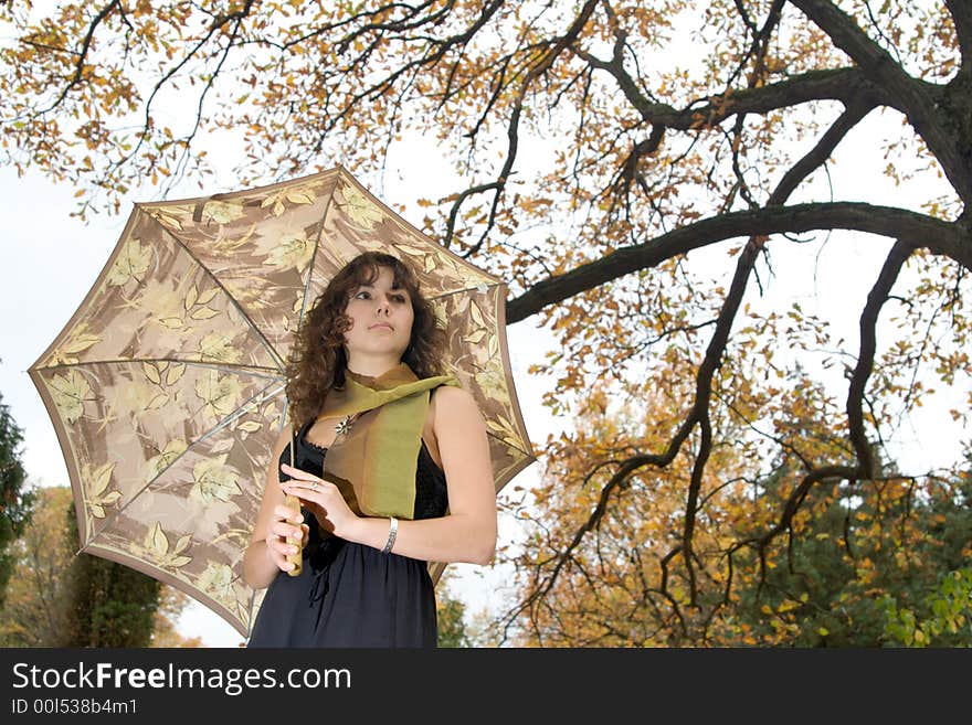 Girl with umbrella standing at autumn park.