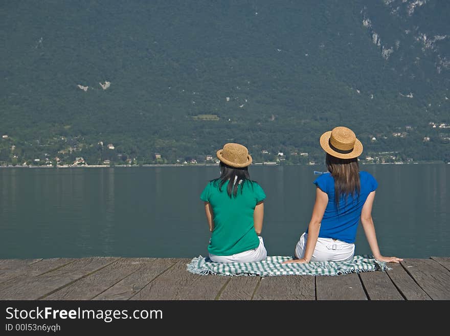 Young woman sitting on a pontoon at the edge of a lake. Young woman sitting on a pontoon at the edge of a lake