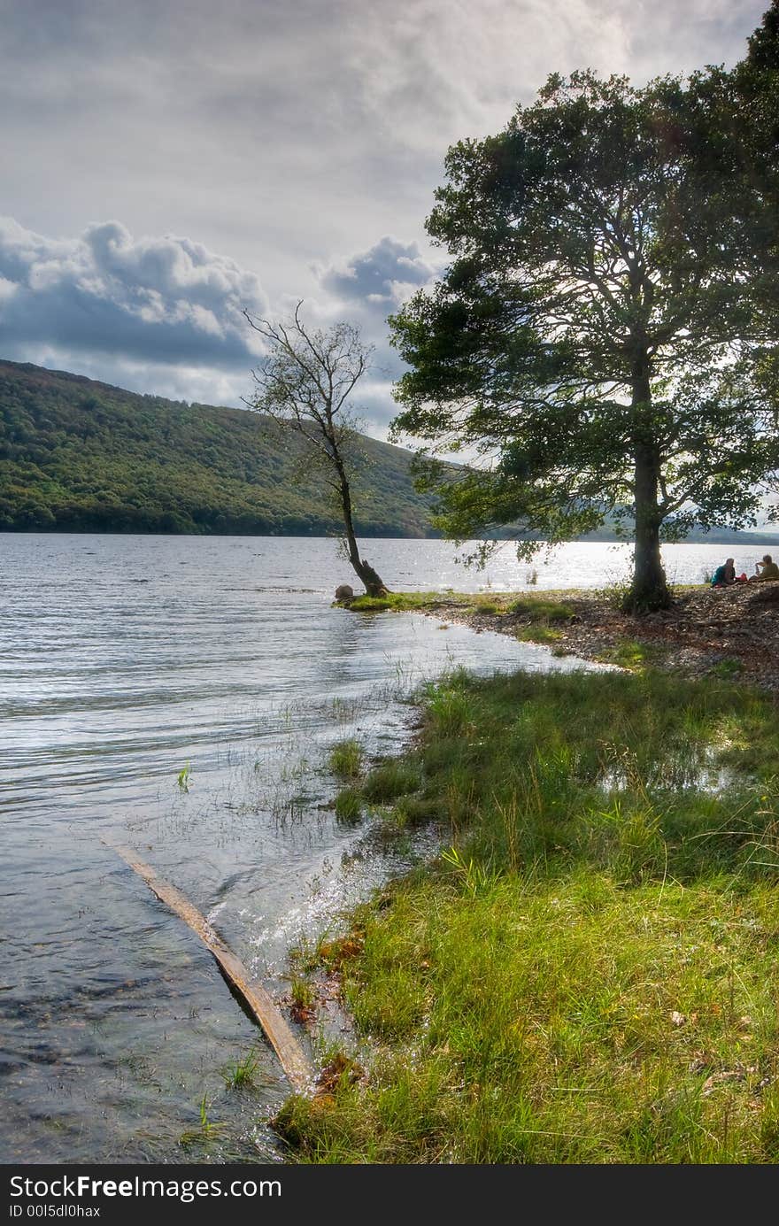 A couple picnicing on the shore of Coniston Water in the English Lake District. A couple picnicing on the shore of Coniston Water in the English Lake District